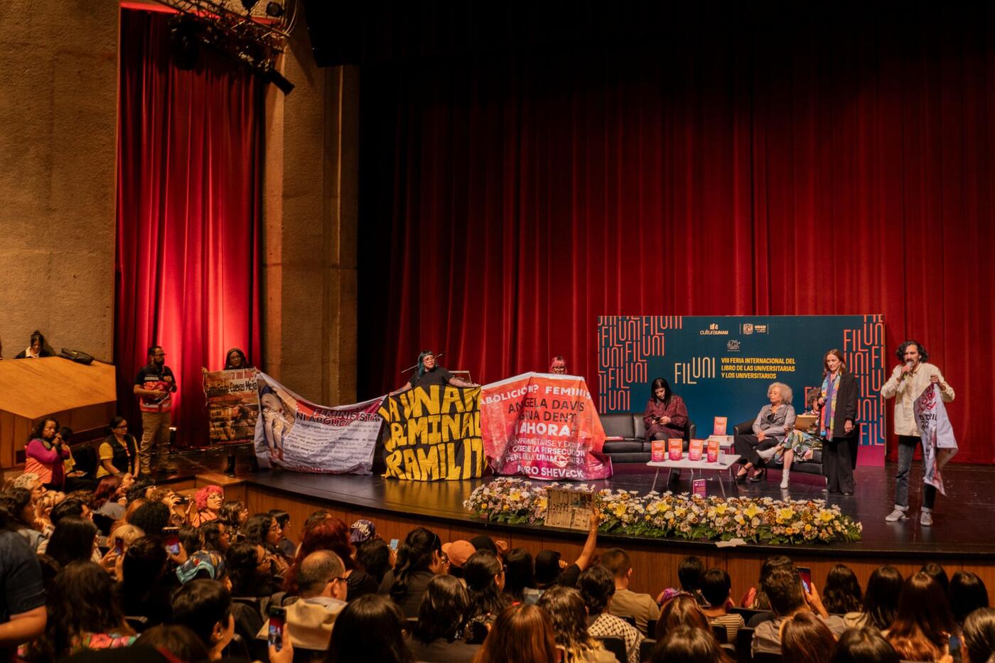 Manifestantes con mantas sobre el escenario de la Sala Miguel Covarrubias.