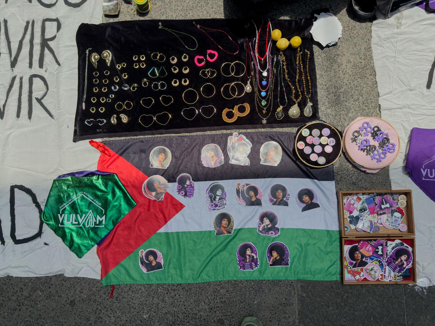 Puesto en el suelo con aretes, calcomanías y una bandera de Palestina.