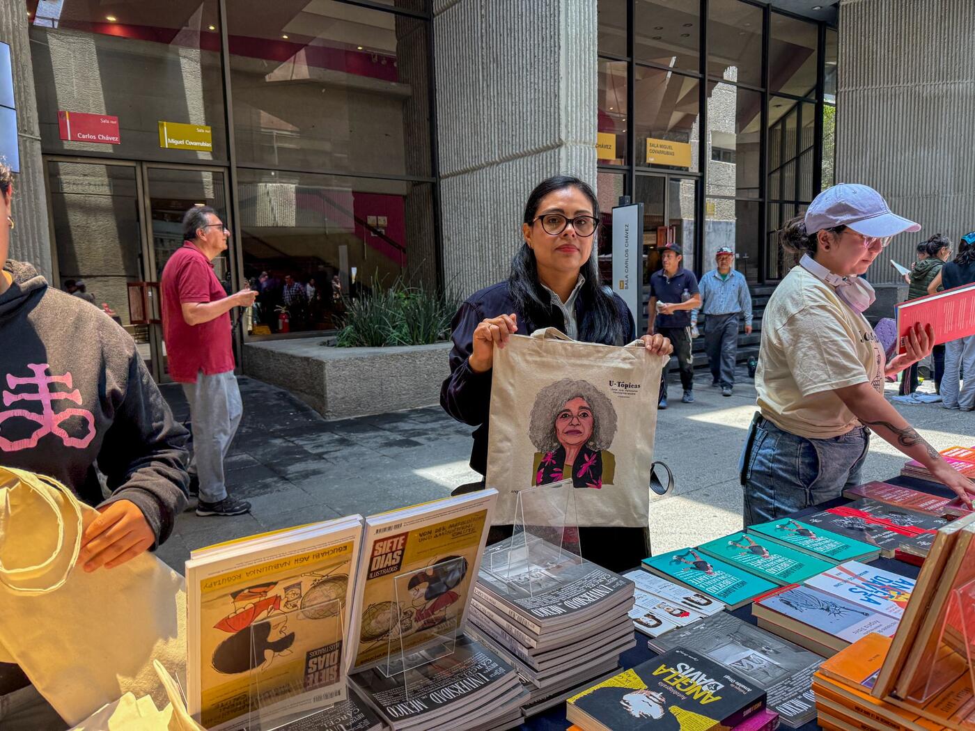 Una asistente muestra una bolsa de tela con el rostro de Angela Davis en un puesto de libros.