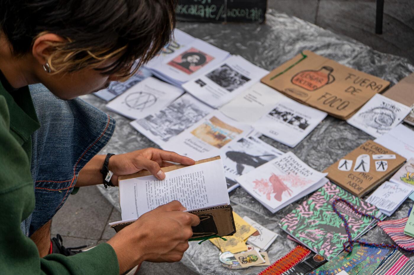 Una persona hojea fanzines extendidos sobre una manta.