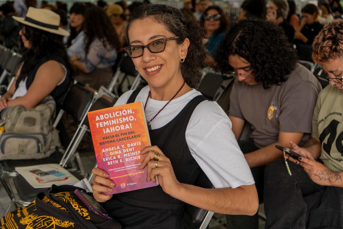 Una asistente sonríe y muestra el libro Abolición, feminismo, ¡ahora!