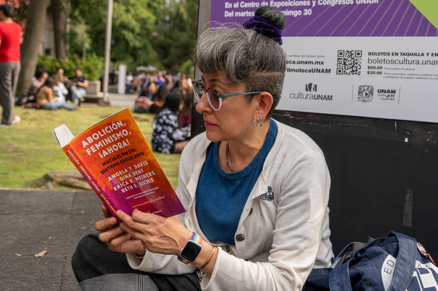 Una mujer lee el libro Abolición, feminismo, ¡ahora! sentada en la explanada.